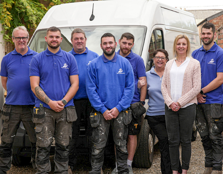 safe and healthy homes team in their blue branded t-shirts with a 10th anniversary blue above