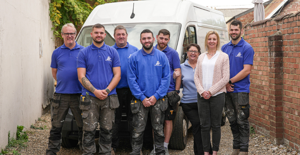 safe and healthy homes team in their blue branded t-shirts with a 10th anniversary blue above