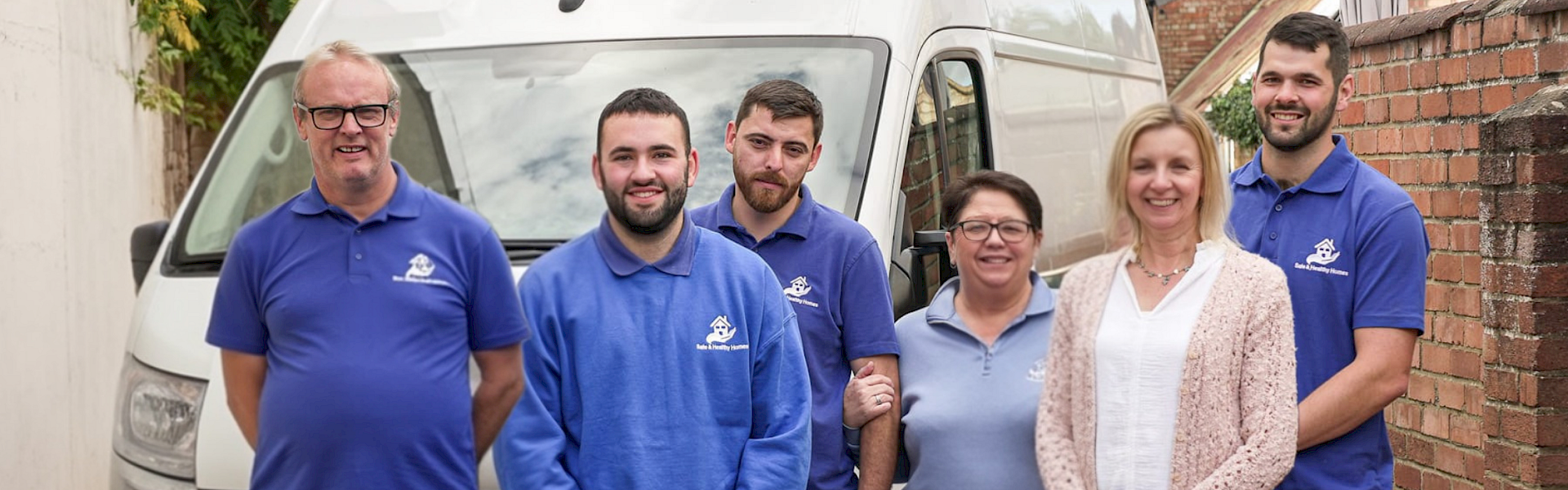 safe and healthy homes team in their blue branded t-shirts with a 10th anniversary blue above